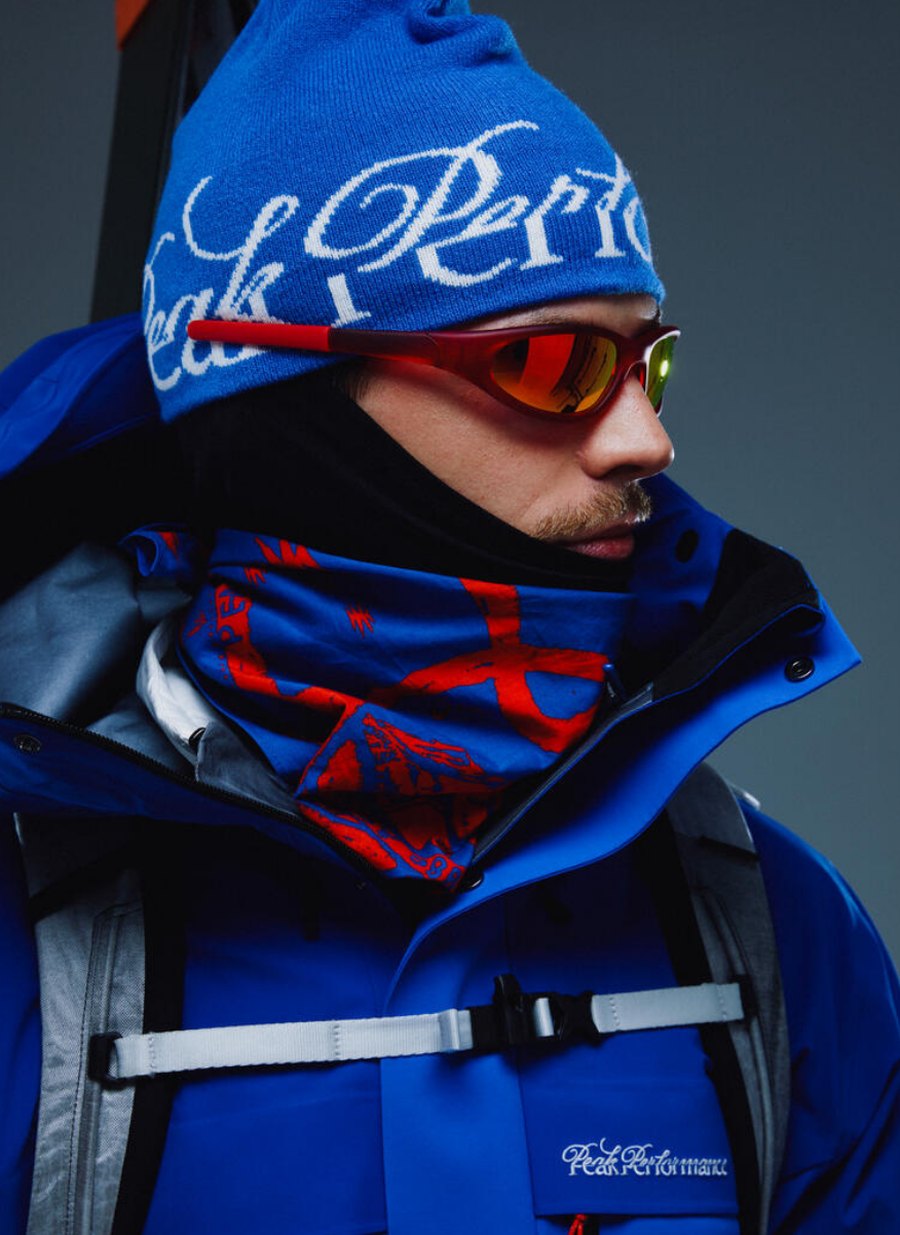 Modell med Peak Performance 40Y mössa, goggles och blå GORE-TEX skidjacka